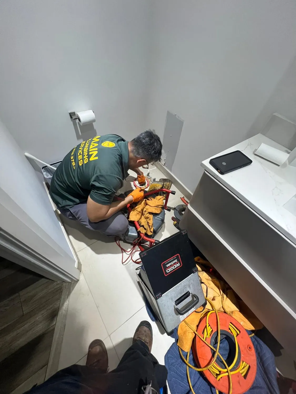 Plumber using a drain camera and machine on a bathroom line