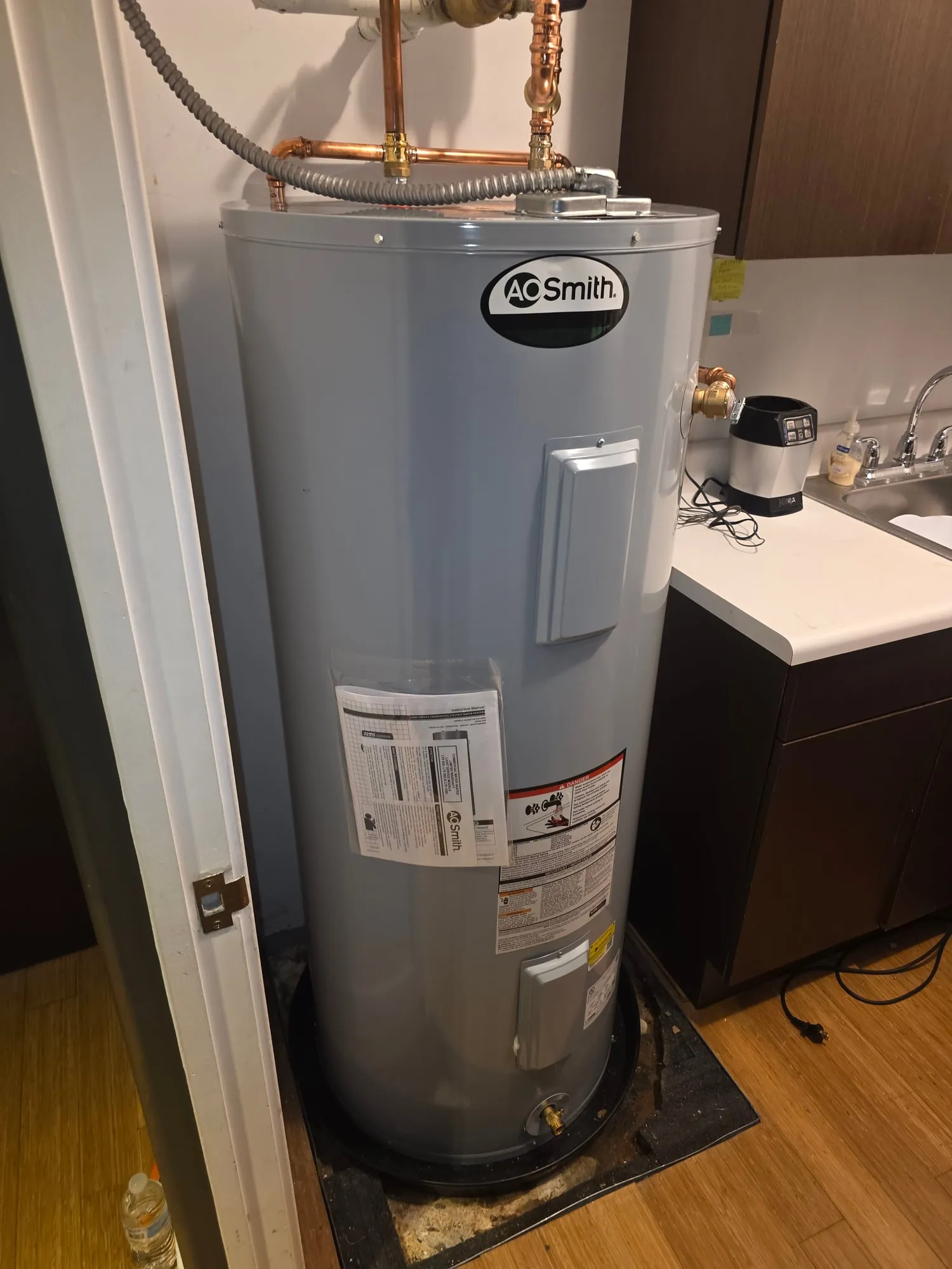 New electric water heater installed in a closet beside a kitchenette