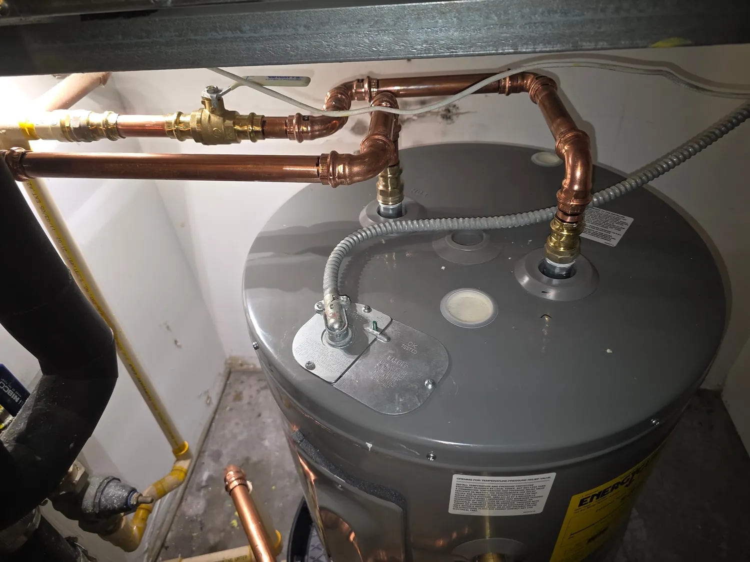 Top of a new electric water heater with fresh copper supply connections