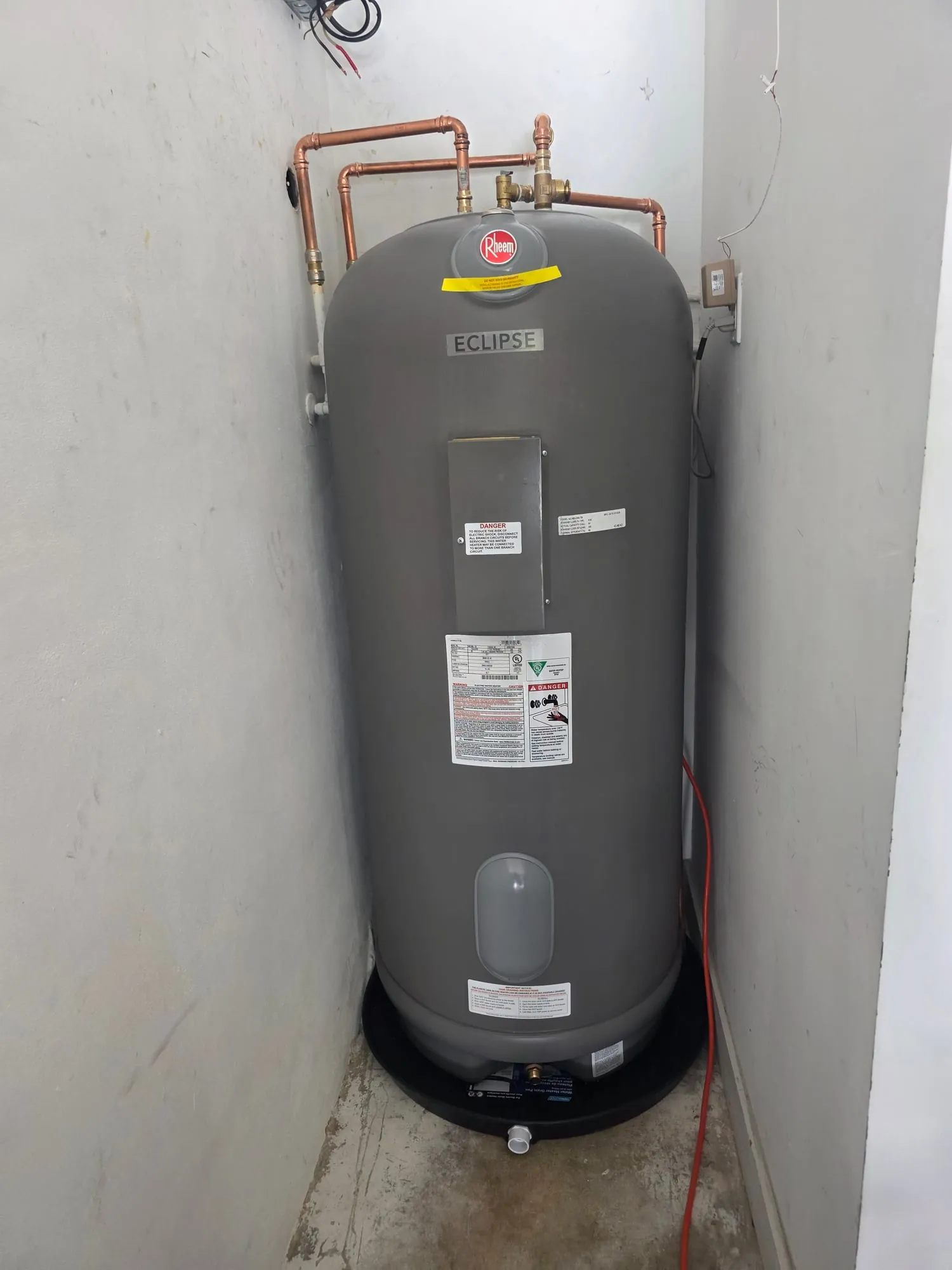 Tall electric water heater installed in a narrow closet