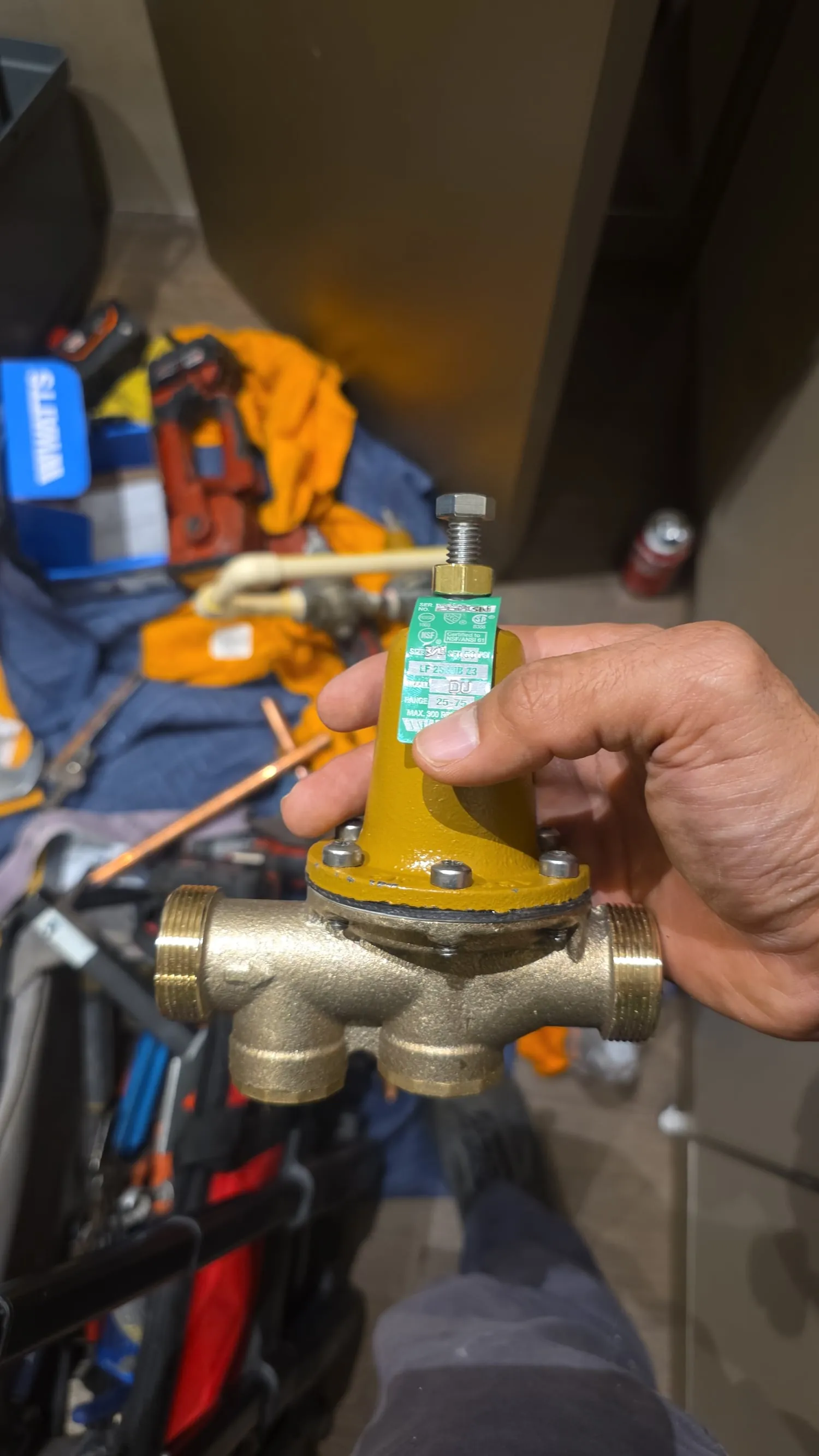 Plumber holding a new pressure-reducing valve before installation