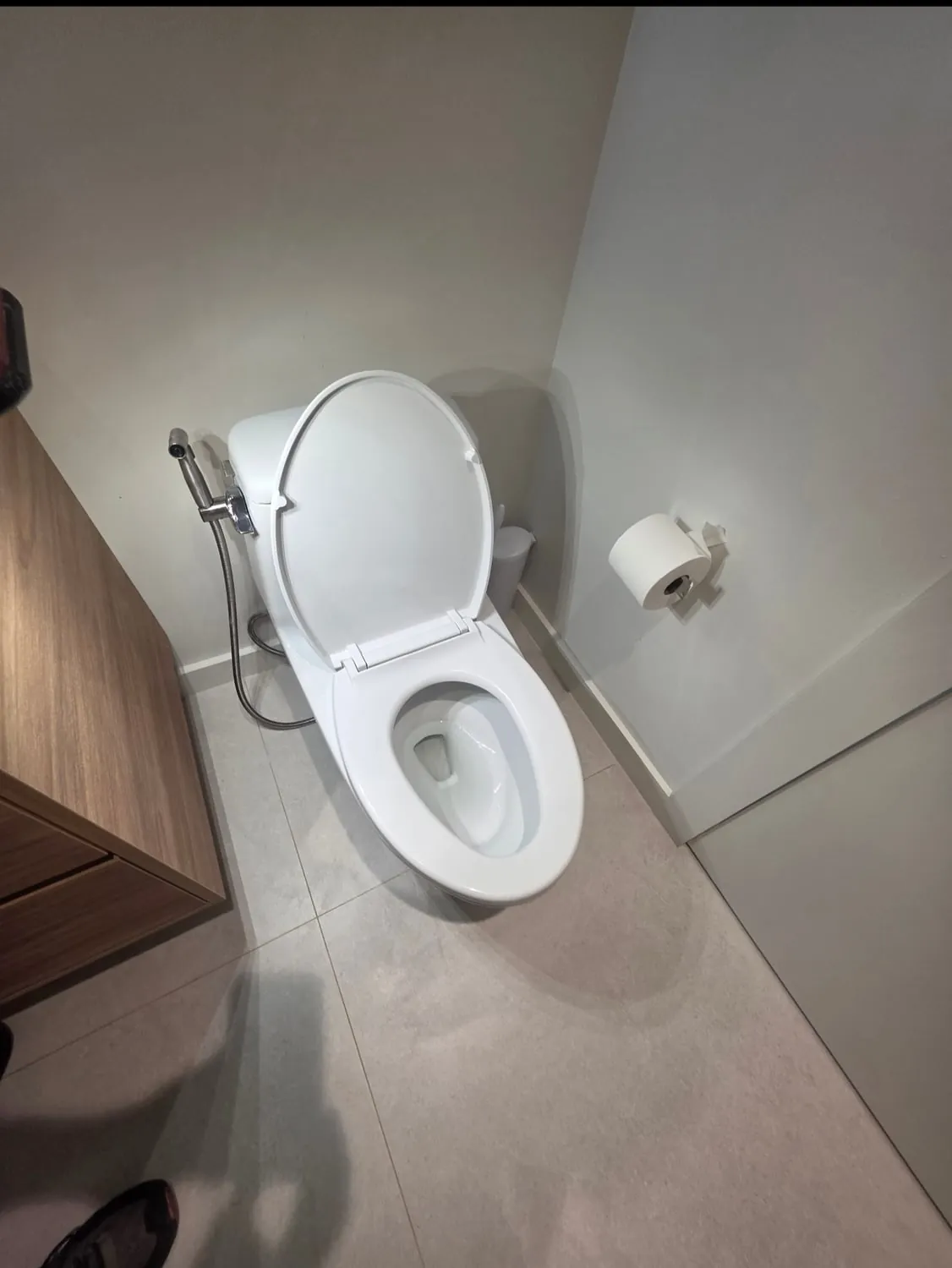 New elongated toilet with a bidet sprayer in a modern bathroom