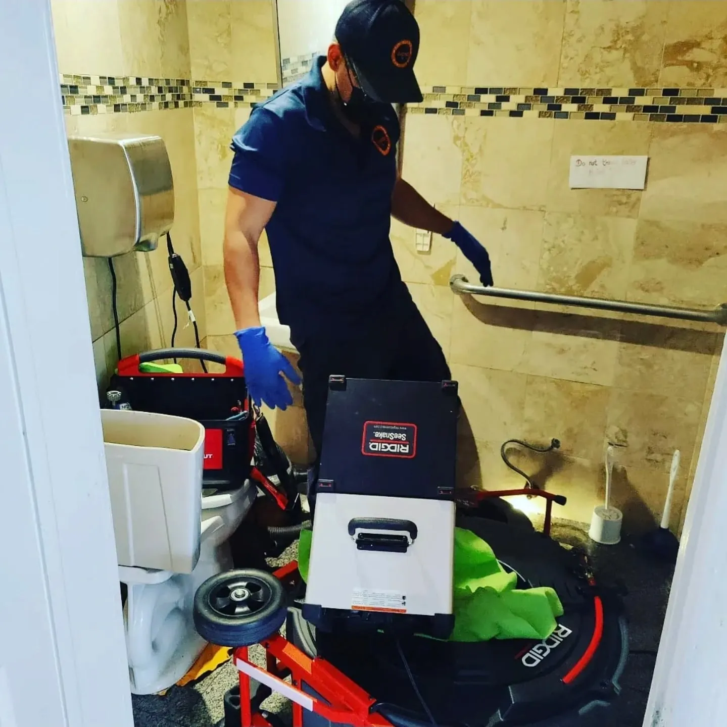Plumber with a drain machine clearing the line in a commercial restroom