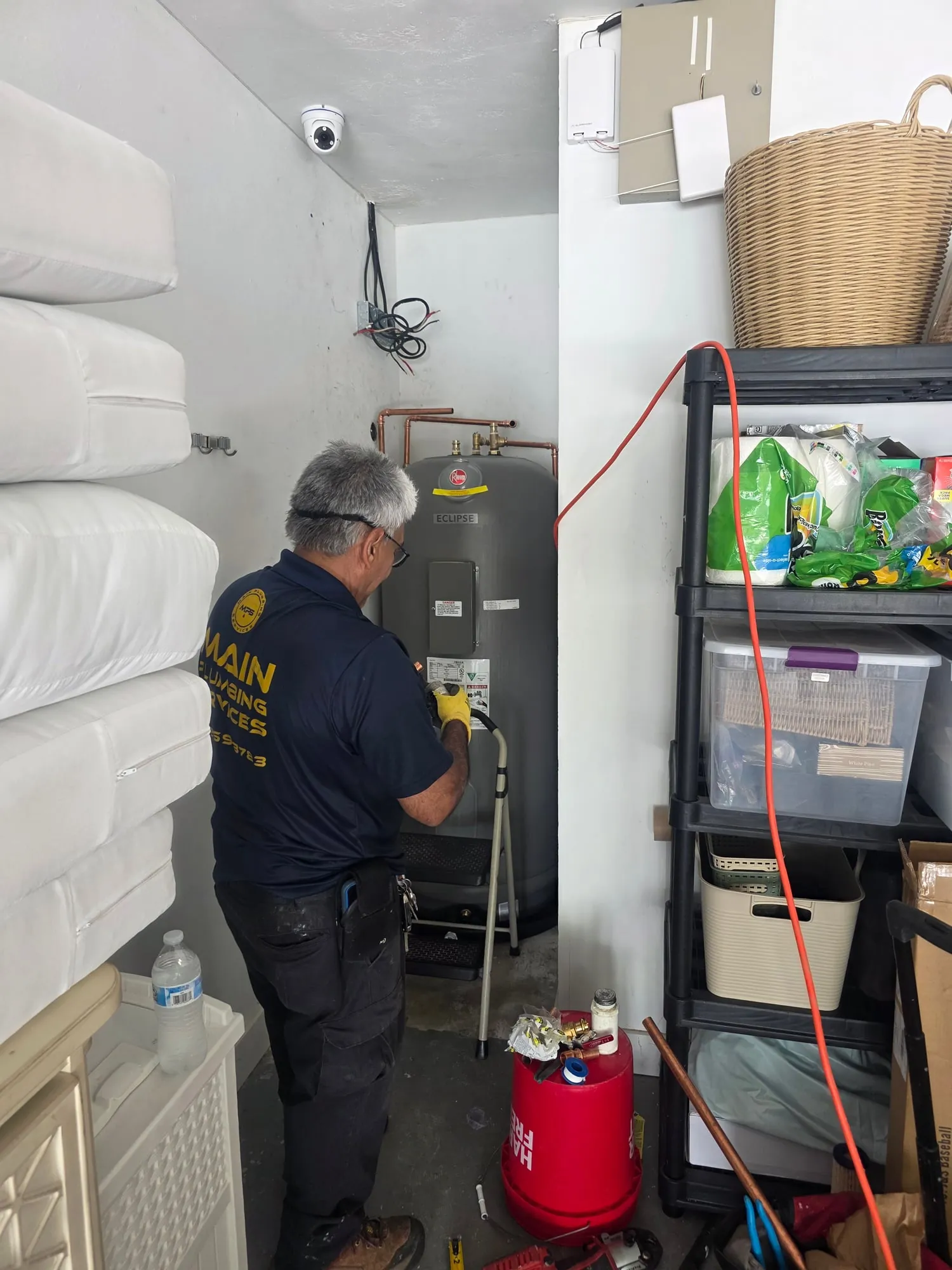 Plumber connecting a new electric water heater in a storage room