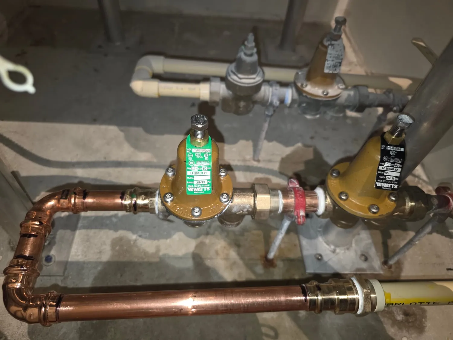 Two new pressure-reducing valves on copper piping in a building mechanical room