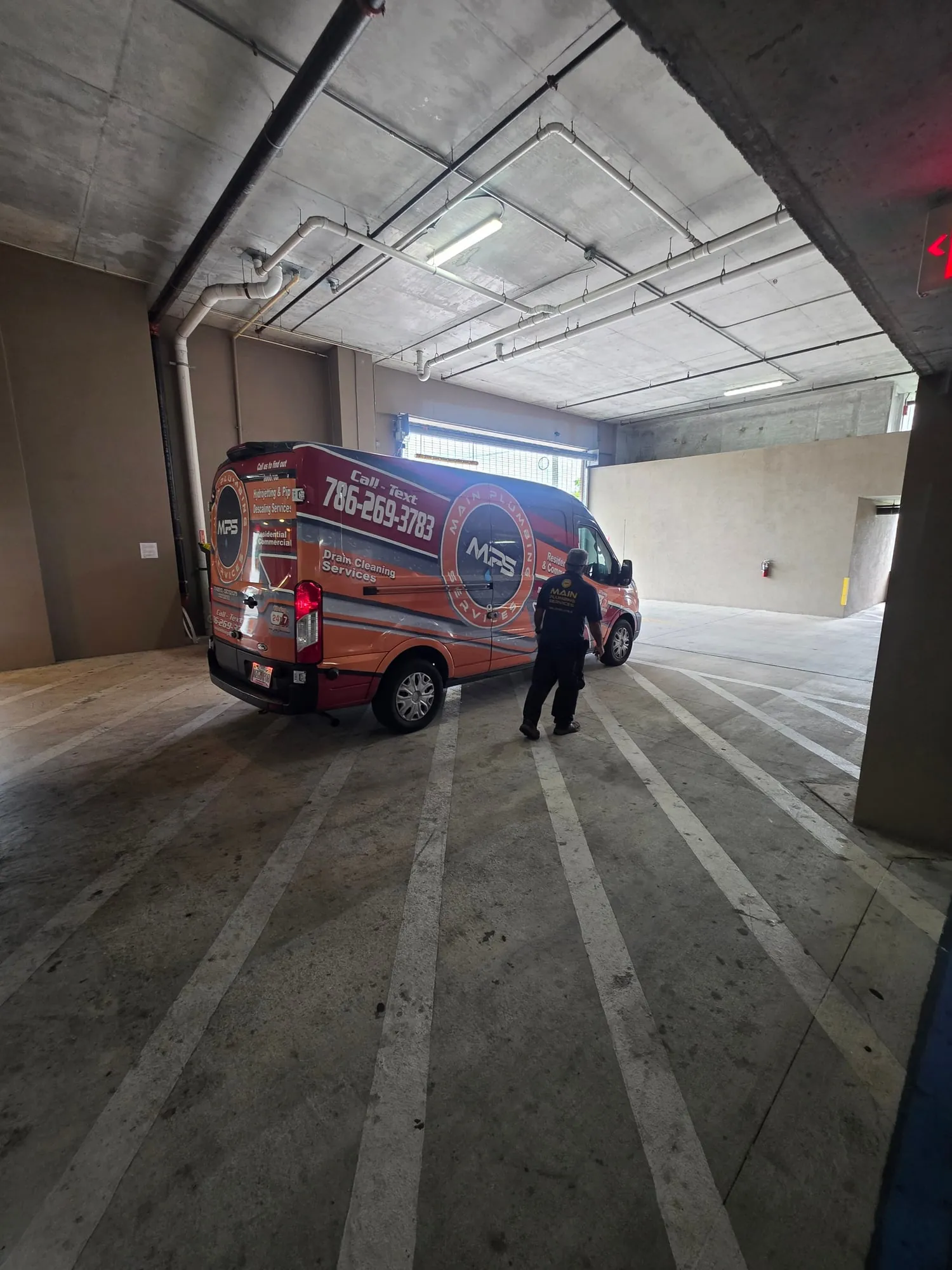 Plumber walking to a service van inside a building parking garage