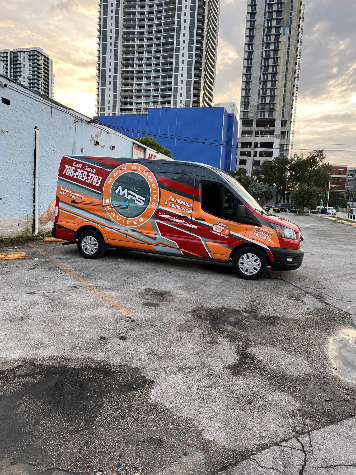 Main Plumbing Services van parked in front of Miami high-rise towers