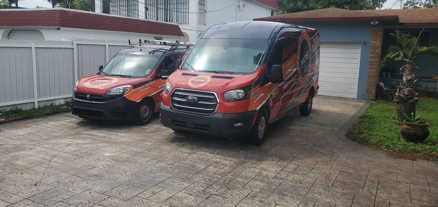 Two Main Plumbing Services vans in the driveway of a Miami home