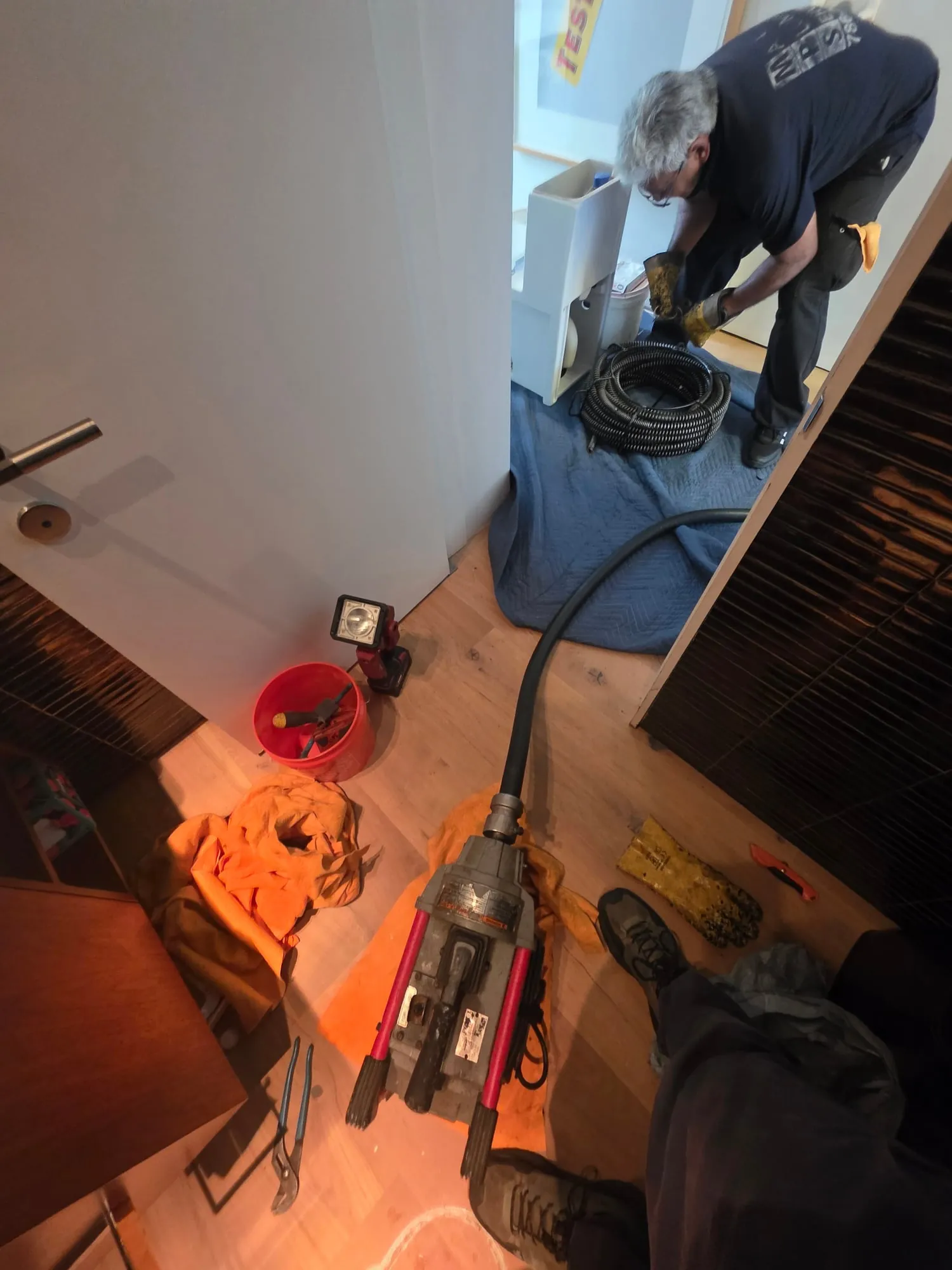Plumber running a drain machine through the toilet drain in a bathroom