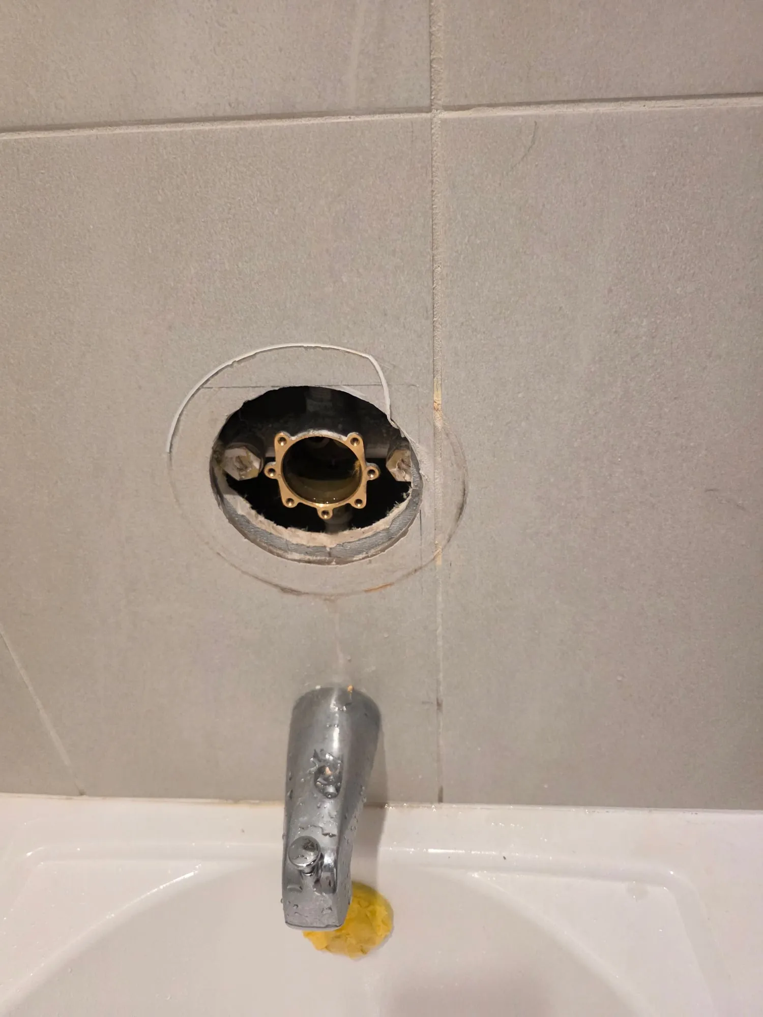 Tub and shower valve opening in a tiled wall above the tub spout