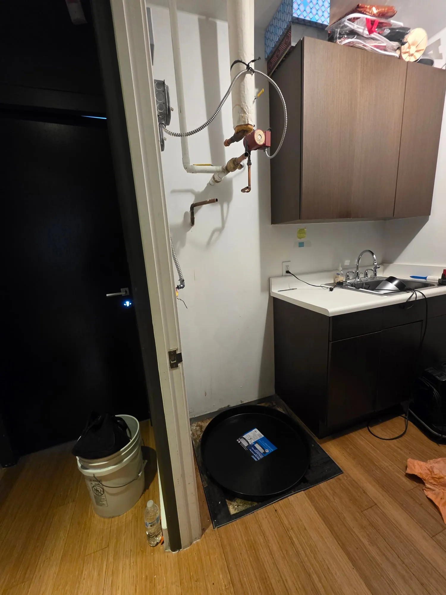 Empty water heater closet with a drain pan next to a kitchenette