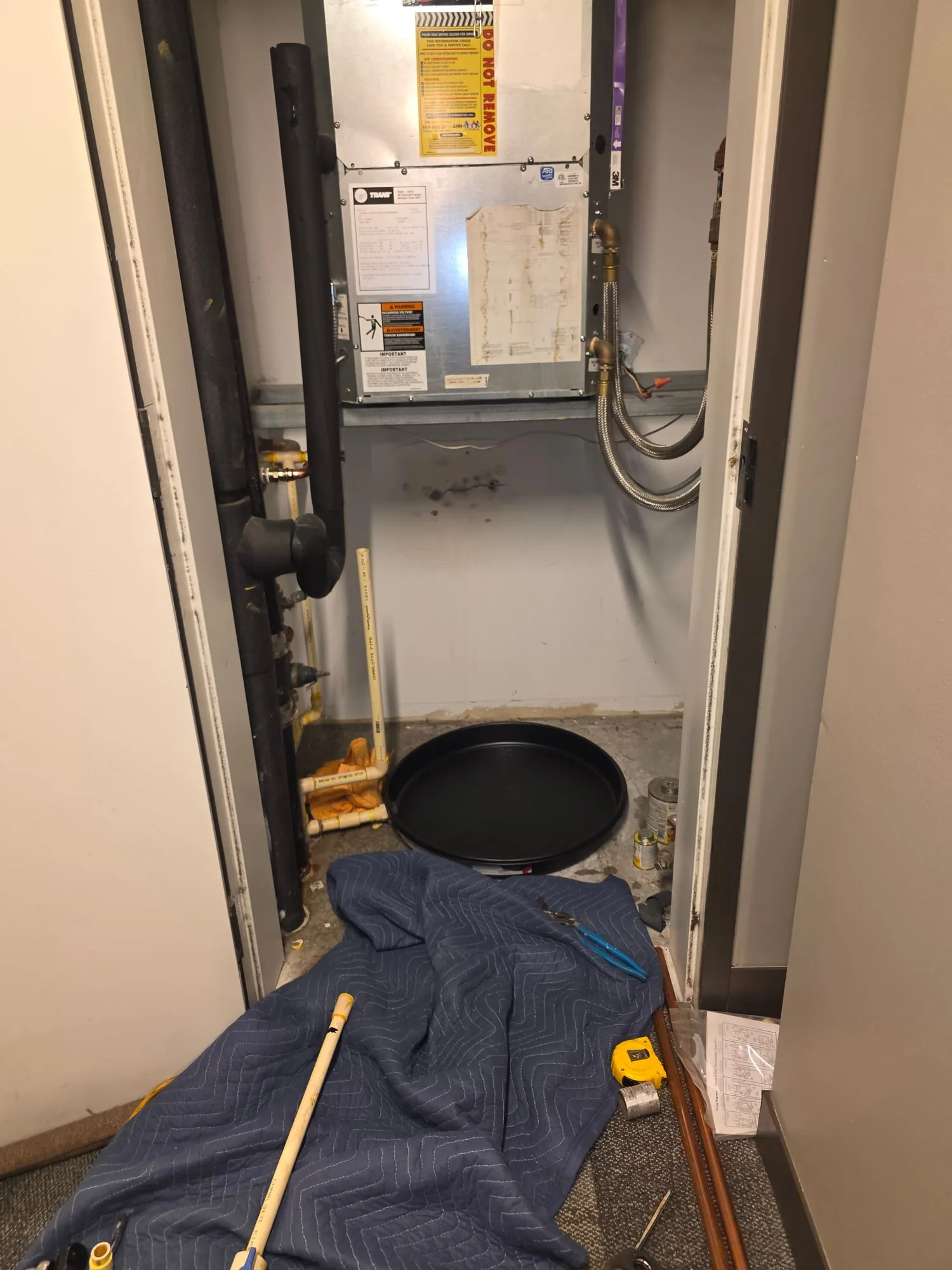 Condo closet with the old water heater removed below the air handler