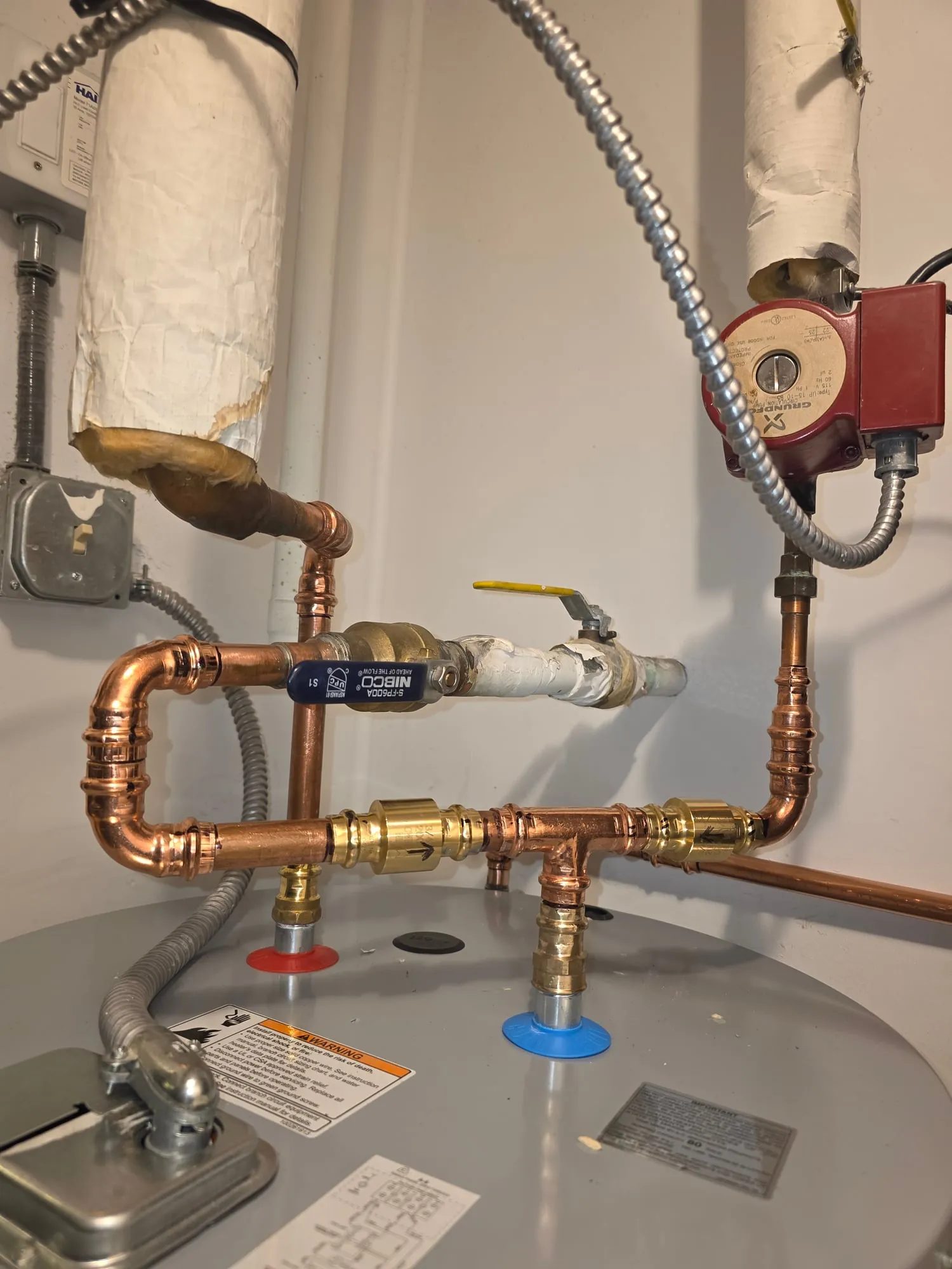 Copper piping with a recirculation pump above an electric water heater