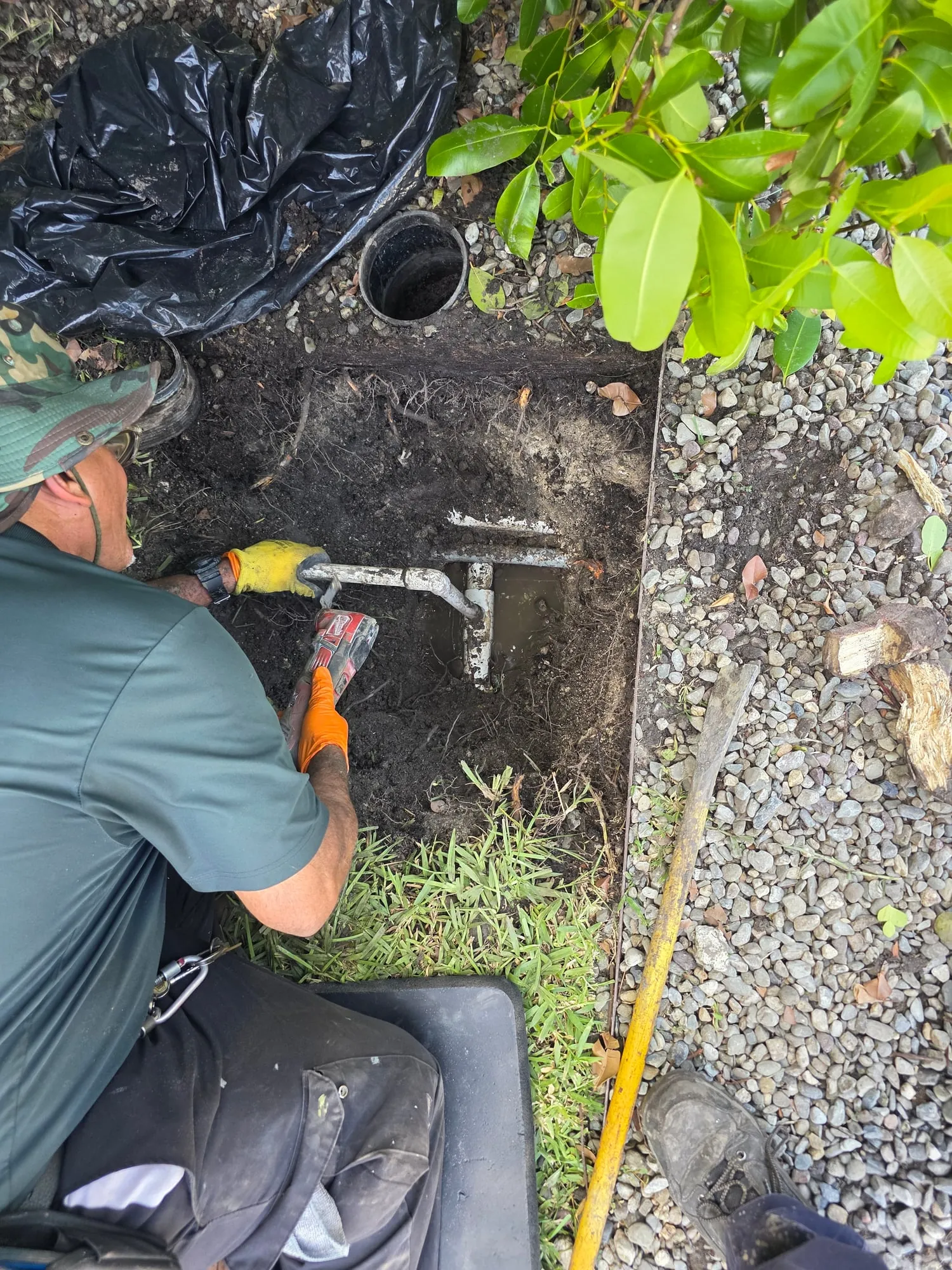 Plumber repairing an exposed water line in a small excavation